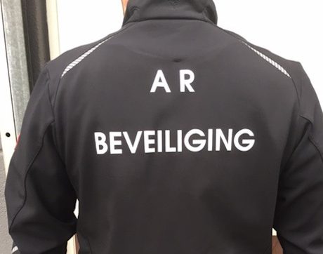 Beveiliger met zwarte jas opschrift achterkant van de jas de tekst A.R. Beveiliging