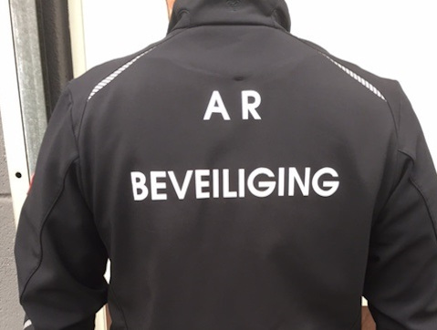 Beveiliger met zwarte jas opschrift achterkant van de jas de tekst A.R. Beveiliging